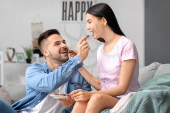 Beautiful young couple eating chocolate at home�