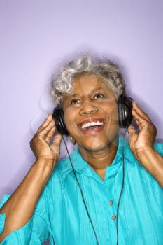 Mature adult African American female listening to headphones.