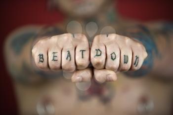 Royalty Free Photo of a Man With Tattoos and Piercings Holding Out His Fists Reading Beat Down