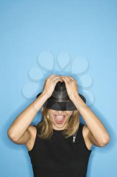 Caucasian young adult female pulling hat down over eyes.
