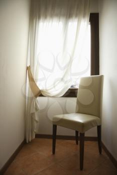 Royalty Free Photo of an Empty Chair by a Window With Drapes in Venice, Italy