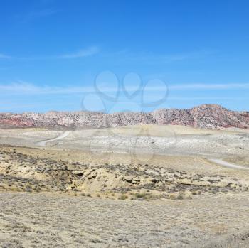 Desert land with rocky cliffs in background of Cottonwood Canyon.