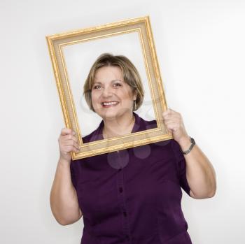 Royalty Free Photo of a Woman Holding a Frame Over Her Face and Smiling