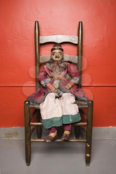 Royalty Free Photo of a Wooden Puppet Sitting on a Chair