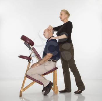 Royalty Free Photo of a Female Massage Therapist Massaging the Beck of a Man Sitting in a Massage Chair