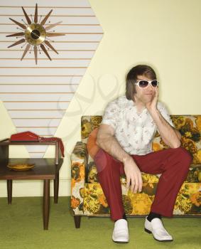Royalty Free Photo of a Man Wearing Sunglasses Sitting on a Retro Sofa