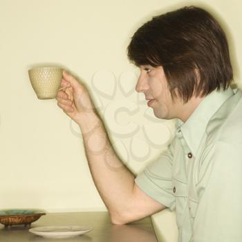 Side view of Caucasian mid-adult man holding up coffee cup.