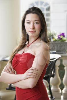 Taiwanese mid adult woman in red dress with arms crossed looking at viewer.