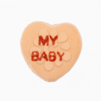 Orange candy heart that reads my baby against white background.