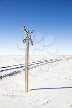 Royalty Free Photo of a Railroad Crossing Sign by Railway Tracks