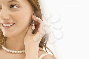 Caucasian bride adjusting her earring.