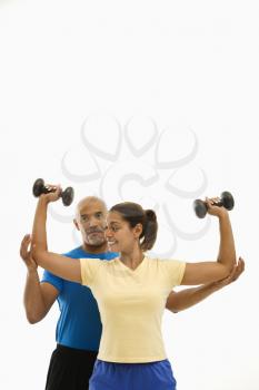 Royalty Free Photo of a Smiling Man Assisting a Woman With Dumbbells