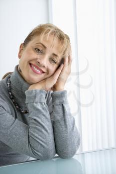 Royalty Free Photo of a Woman Sitting at a Table Smiling