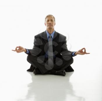 Royalty Free Photo of a Middle Aged Businessman Meditating in a Yoga Lotus Pose on the Floor
