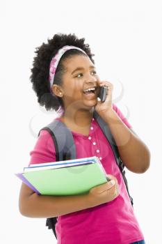 African American girl with books and wearing backpack talking on cell phone.