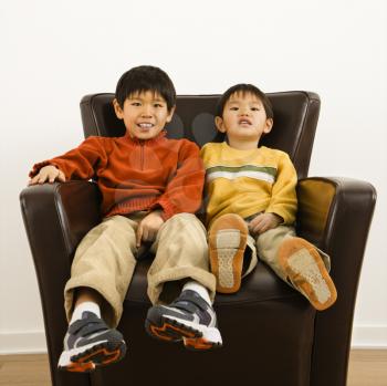 Royalty Free Photo of Two Brothers Sitting in a Chair Smiling