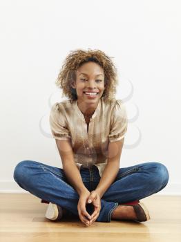 Royalty Free Photo of a Woman Sitting on a Wood Floor Smiling