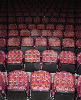 Rows of empty multicolored seats in theater. Vertical shot.