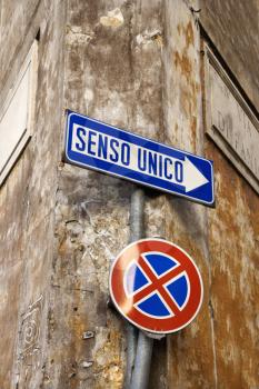 Close-up of Italian street signs, with one indicating 'one way' and the other of a red x through a blue circle. Vertical shot.