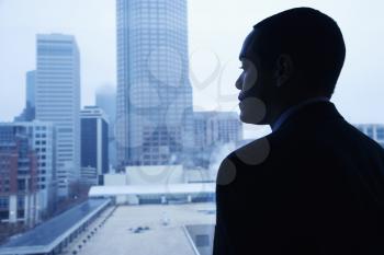 African-American businessman looking out of a window at the city. Horizontal shot.