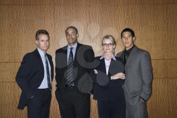 Ethnically diverse businessmen and a businesswoman stand in a lineup as they look towards the camera. Horizontal shot.