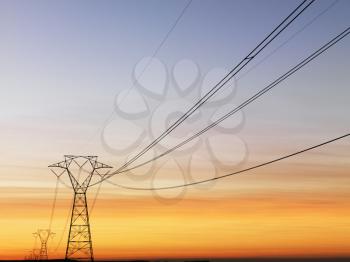 Line of electrical towers and power lines at sunset. Horizontal shot.