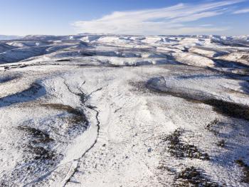 Aerial view of a snow-covered hills with sparse tree coverage. Horizontal shot.