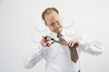 Caucasian middle aged businessman cutting off necktie with scissors.