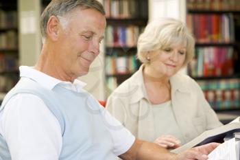 Royalty Free Photo of a Man and Woman Reading in a Library