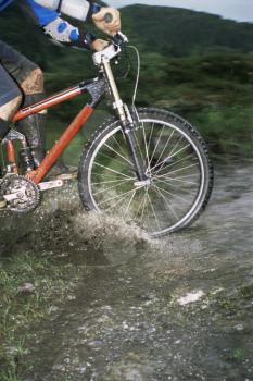 Royalty Free Photo of a Cyclist Riding Through a Stream
