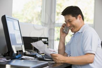 Royalty Free Photo of a Man at the Computer Talking on the Phone