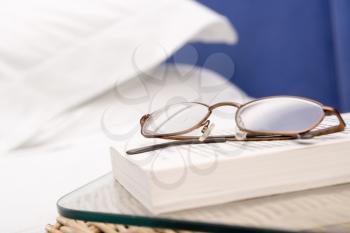 Royalty Free Photo of a Eyeglasses and a Book on a Nightstand