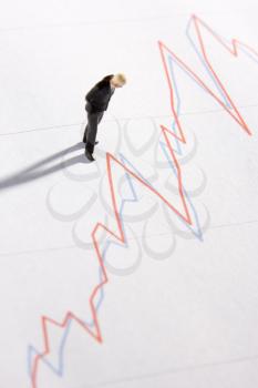 Royalty Free Photo of a Businessman Figurine Looking at a Chart