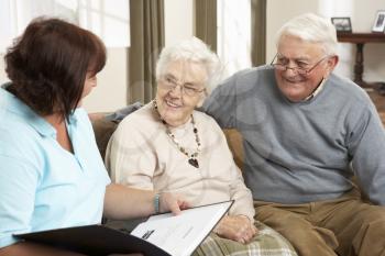 Senior Couple In Discussion With Health Visitor At Home