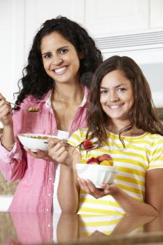Mother and daughter eating cereal and fruit