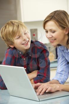 Mother and son using laptop in domestic kitchen