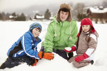 Group Of Children Building Snowman Wearing Woolly Hats