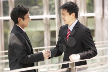 Two Chinese Businessmen Shaking Hands Outside Office