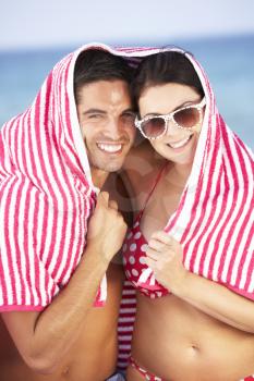 Couple Sheltering From Sun On Beach Holiday