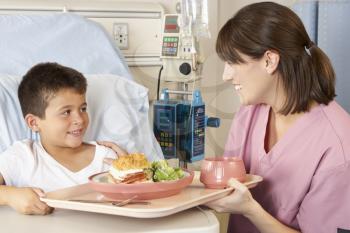 Nurse Serving Child Patient Meal In Hospital Bed