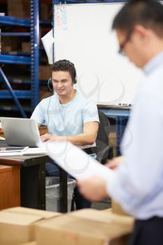 Worker In Warehouse Wearing Headset And Using Laptop