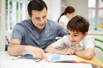Father Helping Son With Homework Using Digital Tablet