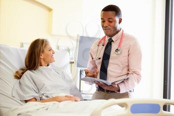 Doctor Talking To Female Patient In Hospital Room