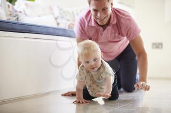Father And Young Son Crawling Around Room Together