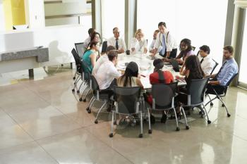 Businessman Addressing Meeting Around Boardroom Table