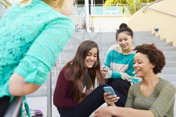 Female High School Students Sitting Outside Building