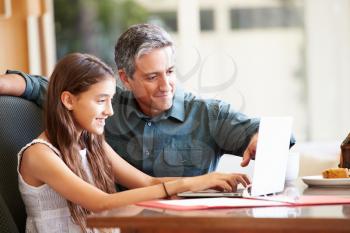 Father And Teenage Daughter Looking At Laptop Together