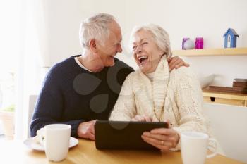 Senior Couple Using Digital Tablet At Table