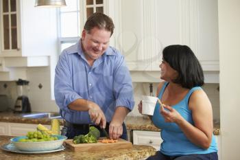 Overweight Couple On Diet Preparing Vegetables In Kitchen