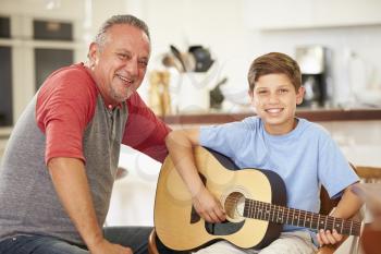 Grandfather Teaching Grandson To Play Guitar